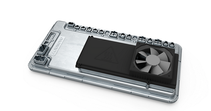 Close-up view of an automotive high-performance computer (HPC) unit featuring a metallic housing with multiple connector ports along the top edge. A black cooling module with a triangular heat warning symbol and an integrated fan is mounted on the surface, indicating active thermal management for high-performance processing in advanced vehicle systems.