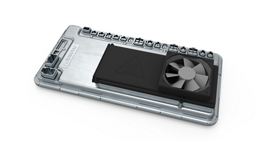 Close-up view of an automotive high-performance computer (HPC) unit featuring a metallic housing with multiple connector ports along the top edge. A black cooling module with a triangular heat warning symbol and an integrated fan is mounted on the surface, indicating active thermal management for high-performance processing in advanced vehicle systems.