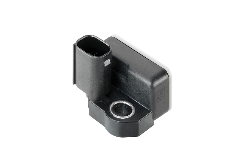 Nahaufnahme eines Beschleunigungssensors mit einem rechteckigen schwarzen Gehäuse mit einem Anschluss und einer Befestigungsbohrung mit Metallverstärkung. Das Design unterstützt die analoge Signalausgabe für Automobilanwendungen.
