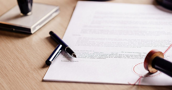 Image of a document lying on a desk with a stamp and pen