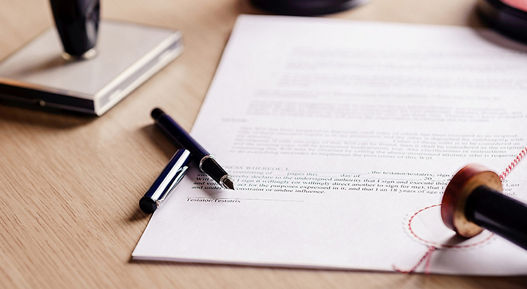 Image of a document lying on a desk with a stamp and pen