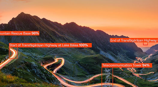 Bird's-eye view of a road illuminated by orange light in a Romanian mountain landscape. Several elements in the photo are marked with orange rectangles, which are part of AI-empowered object recognition and image analysis. Each rectangle is labeled with a designation and a percentage indicating the probability of recognition or model confidence.