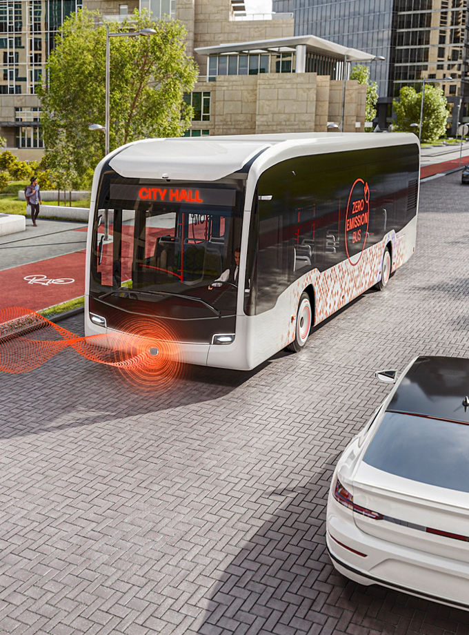 The picture shows an electric city bus using the AVAS acoustic warning system for electric vehicles to alert a cyclist riding on the right-hand side of the bus on a bike path.