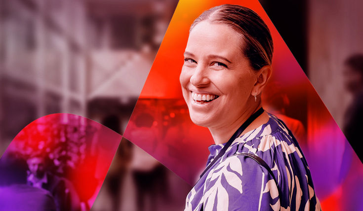 Individual wearing a blue and white patterned outfit, positioned in front of a blurred indoor setting with dynamic orange and purple graphic overlays.