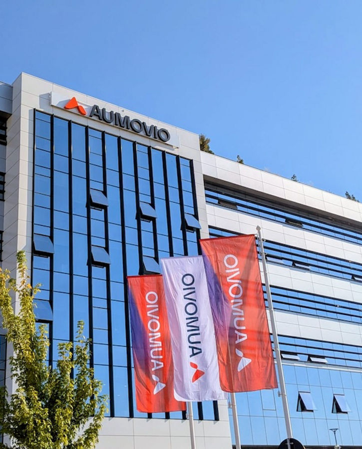 A photo of a building with a large AUMOVIO logo and AUMOVIO flags in front of it. We are the go-to partner for comprehensive testing and analysis services for electronic and mechatronic components – supporting our clients globally and across the entire product lifecycle.