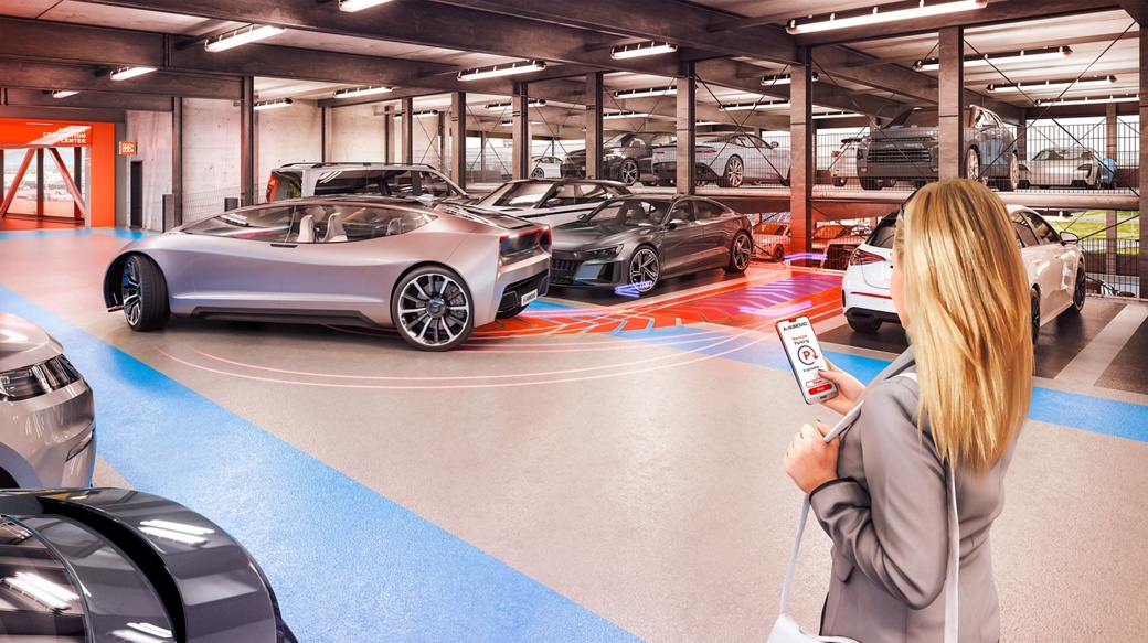 A woman uses her smartphone to automatically move a futuristic vehicle out of its parking space in a parking garage.