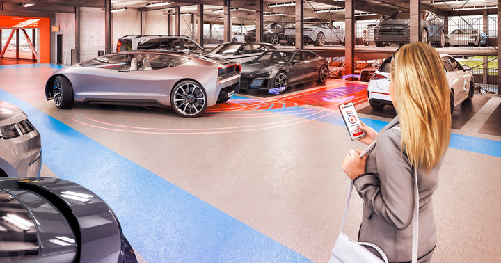 A woman uses her smartphone to automatically move a futuristic vehicle out of its parking space in a parking garage.