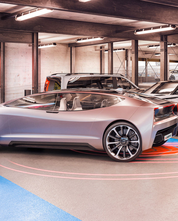 A woman uses her smartphone to automatically move a futuristic vehicle out of its parking space in a parking garage.