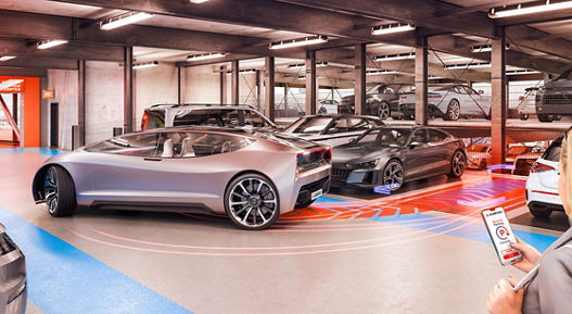 A woman uses her smartphone to automatically move a futuristic vehicle out of its parking space in a parking garage.