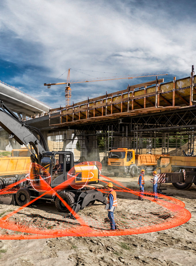 The image shows a construction site scene with several construction vehicles. Several orange sensor lines extend from the digger to the ground, as an example of camera systems.