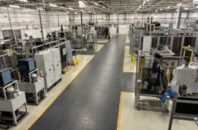 The image shows a assembly line in a manufacturing facility. Find out how AUMOVIO UK can support you with over 15 different assembly lines designed to serve a wide range of markets, from small assemblies and complex builds to high-volume, fully automated production lines.