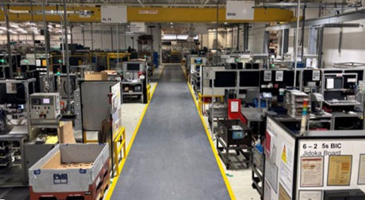 The image shows a production line for contract manufacturing. For over 50 years, AUMOVIO UK has been serving a diverse customer base, ranging from automotive OEMs across Europe to local UK manufacturers, with both small-scale and high-volume production capabilities, and a capacity to manufacture over 12 million parts per year.