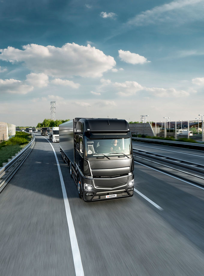 The image shows a truck on a highway as an example of the AUMOVIO control unit portfolio, which offers reliable and easy-to-use solutions designed to meet various customer needs.
