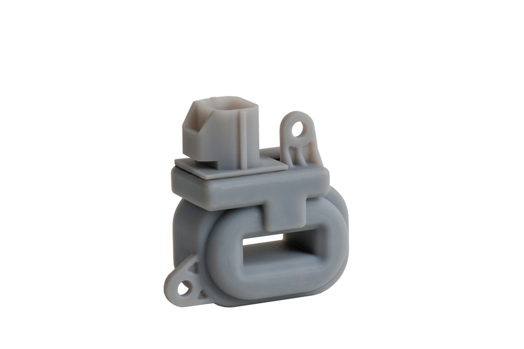 Weißer Kunststoff-Hall-Effekt-Stromsensor mit einem rechteckigen Gehäuse und einer Aussparung in der Mitte für die Platzierung des Leiters. Die Komponente verfügt über zwei Befestigungslöcher und einen Anschluss auf der Oberseite für die Signalübertragung. Konzipiert für die Einpunkt-Strommessung in Automobilsystemen.