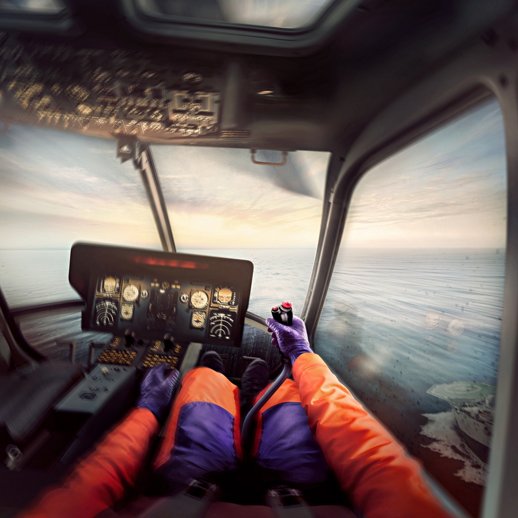 Blick aus dem Cockpit eines Hubschraubers auf die Steuerelemente und Instrumente, mit Blick auf die malerische Meereslandschaft durch die Windschutzscheibe.