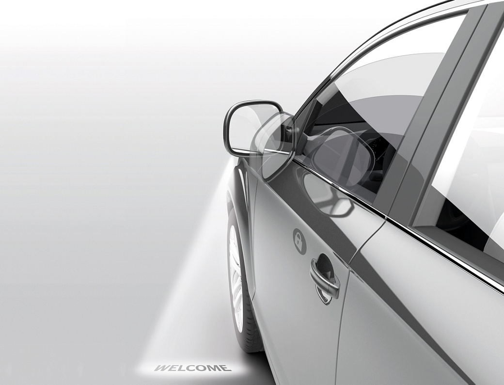 Nahaufnahme einer Autotür mit einem Bodenprojektionslicht, das das Wort „WELCOME” anzeigt. Veranschaulicht fortschrittliche Türsteuerungs- und Beleuchtungsfunktionen für ein verbessertes Benutzererlebnis.