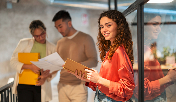 The image Education at AUMOVIO shows three students at a university or school with documents in their hands. With an apprenticeship, a dual study program, or a student internship, you can find out where your strengths lie and how you can use them at an employer that is helping to shape the mobility of the future.