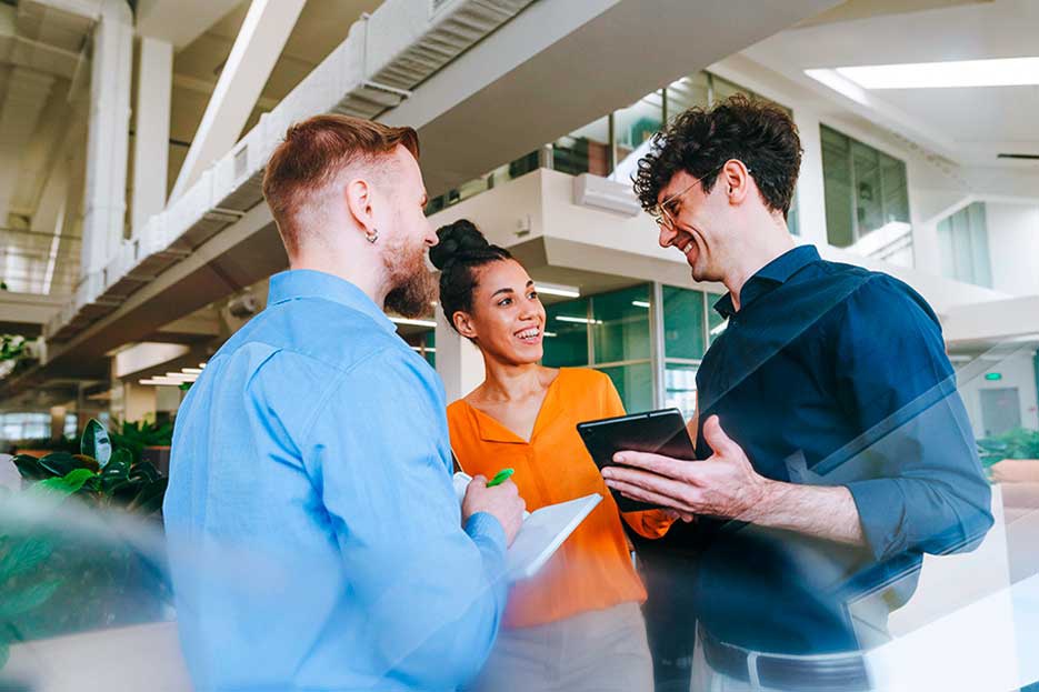 The image education on an equal level, which shows three students talking to each other in a school building, represents an educational community where respectful interaction is not a one-way street. Whether we are trainees, dual students, or instructors, we are all part of an appreciative work and team culture at AUMOVIO.