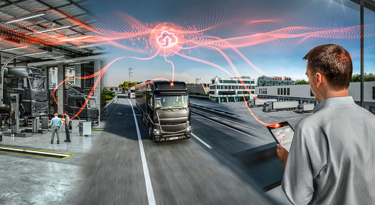 Connected fleet management concept showing heavy-duty trucks in a modern service workshop and on a highway. A person monitors vehicle data on a tablet while cloud-based connectivity is visualized with red digital lines linking trucks to a central cloud icon. The scene combines indoor maintenance and outdoor logistics under bright daylight.