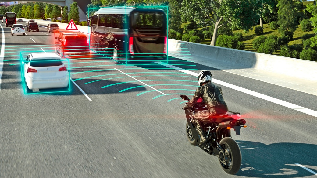 The image shows a traffic situation with heavy traffic. A motorcyclist is riding in the middle lane of a highway. A car in front of him brakes; the motorcycle uses radar sensors to scan the area in front of it, detects the braking vehicle, and alerts the motorcyclist.
