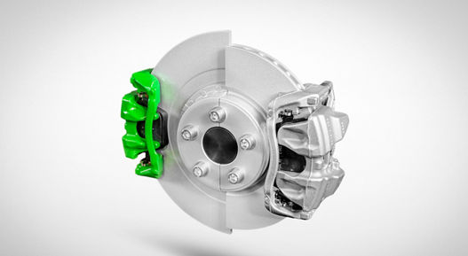 Automotive brake disc with two calipers mounted on opposite sides, one in bright green and the other in silver, illustrating a dual-caliper braking system.