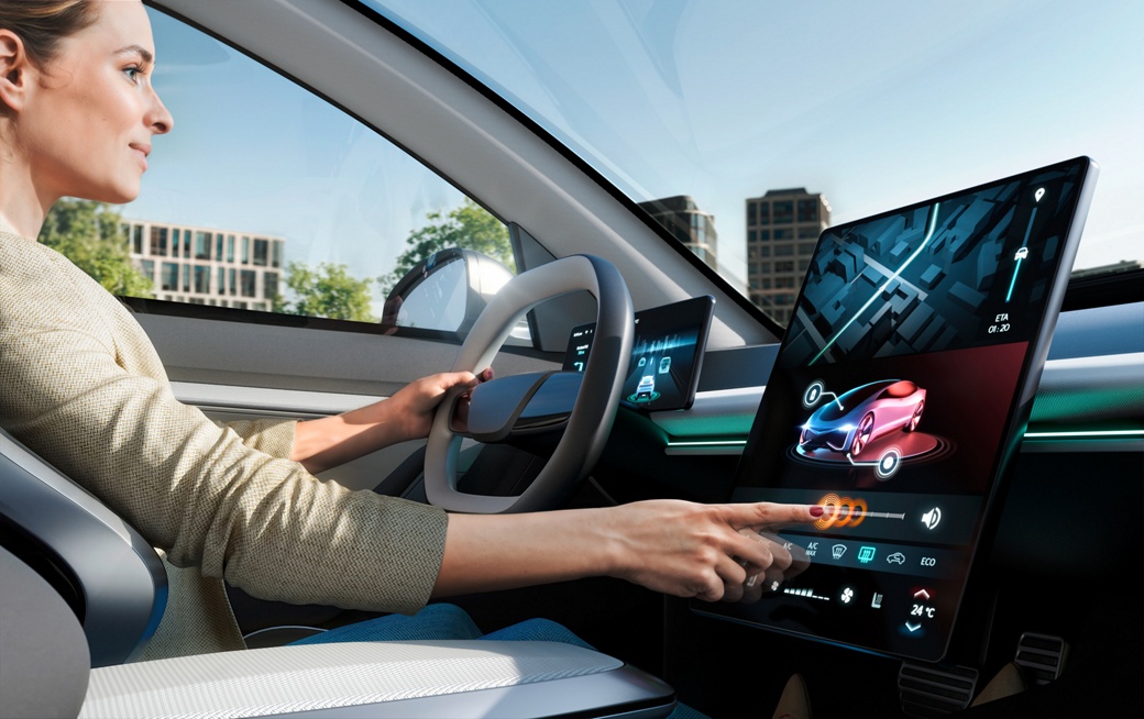 Image of a woman in a vehicle interior adjusting the volume on a dashboard display with her finger. Orange highlights show haptic feedback from touching the display. 