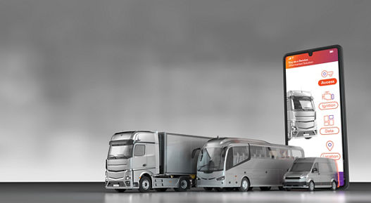 The image shows three commercial vehicles in front of an extremely large smartphone, on which you can see AUMOVIO's digital access solution CoSmA@CV as an app. The AUMOVIO smartphone-based access solution “CoSmA@CV” does not require a physical key and therefore propels the access and engine start system of a truck into the digital age.