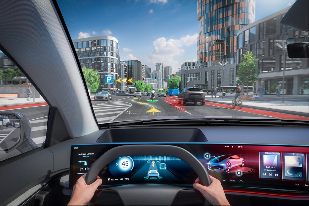 Bild eines futuristischen Fahrzeuginnenraums mit Blick durch die Windschutzscheibe. Navigations-, Verkehrs- und Warninformationen werden vom spiegellosen Augmented-Reality-Head-up-Display direkt auf die Windschutzscheibe projiziert, genau dort, wo der Fahrer sie benötigt.