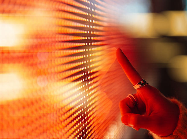 Female hand touching illuminated orange digital screen. Technology and innovation. Connecting to the future.
