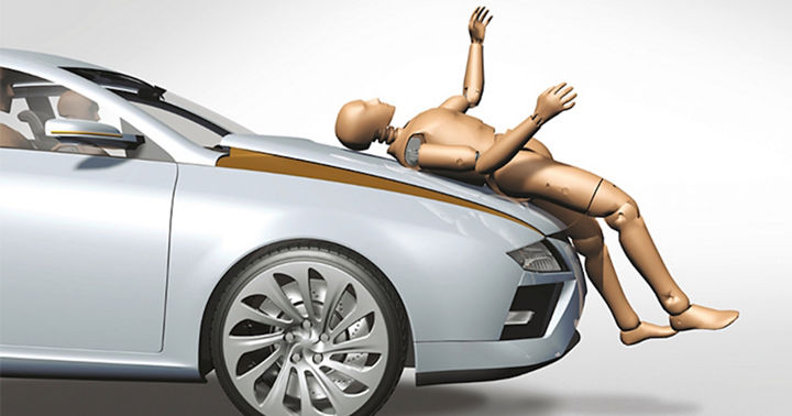Image of a crash test dummy lying on a hood. A pedestrian protection dummy is used for component testing to ensure both occupant and pedestrian safety under various impact conditions. Out-of-Position (OOP) scenarios, airbag deployment trials, and ejection mitigation strategies are evaluated to verify system reliability. Additionally, tensile tests, structural assessments, and bumper pendulum tests are conducted to analyze material strength and energy absorption. These combined methods provide a comprehensive approach to validating safety systems and improving overall crash performance.
