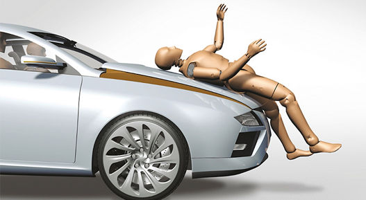 Image of a crash test dummy lying on a hood. A pedestrian protection dummy is used for component testing to ensure both occupant and pedestrian safety under various impact conditions. Out-of-Position (OOP) scenarios, airbag deployment trials, and ejection mitigation strategies are evaluated to verify system reliability. Additionally, tensile tests, structural assessments, and bumper pendulum tests are conducted to analyze material strength and energy absorption. These combined methods provide a comprehensive approach to validating safety systems and improving overall crash performance.