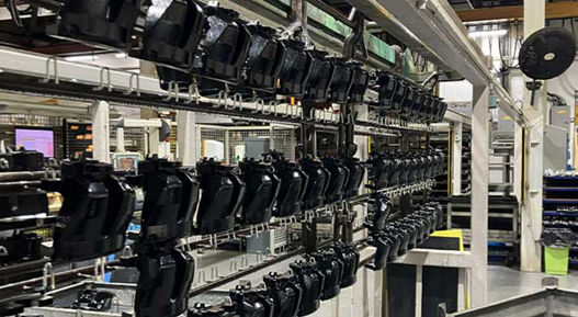 The image shows a assembly line for zinc and zinc nickel coated automotive parts. AUMOVIO UK plating services - zinc and zinc nickel plating specialists.