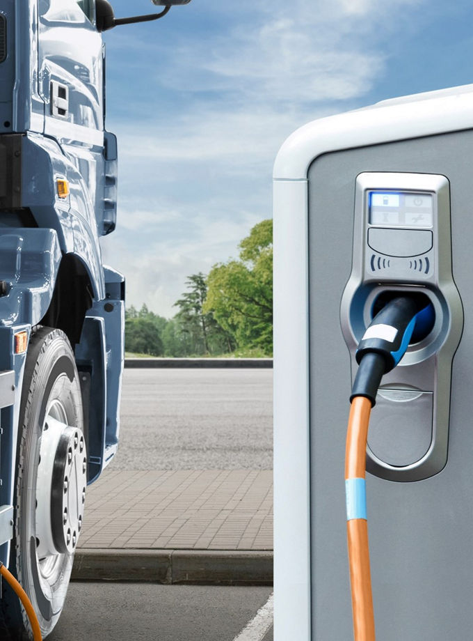 The photo shows an electric truck being charged at a charging station. 