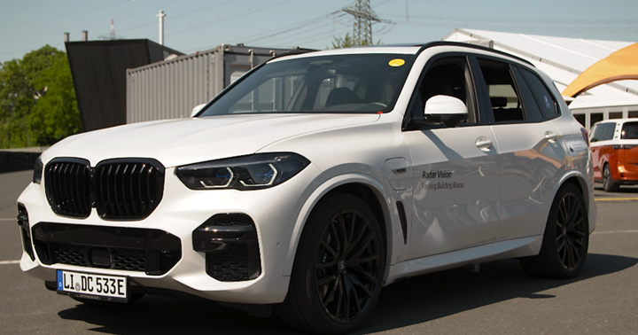 White SUV equipped with radar vision technology for automated parking, displayed outdoors at a tech showcase with visible branding on the front door.