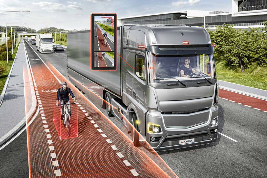 Truck turn-assist system detecting a pedestrian with a bicycle in the vehicle's blind spot, highlighting the person in a warning frame to prevent a collision
