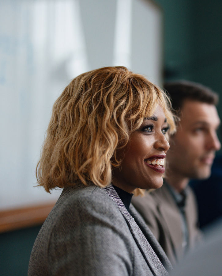 Close up shot of a beautiful smiling businesswoman, sitting at her desk at the office, looking down and using her laptop computer.