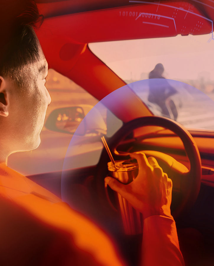Driver inside a modern car holding the steering wheel, with an orange overlay and digital interface graphics representing autonomous driving and safety technology.