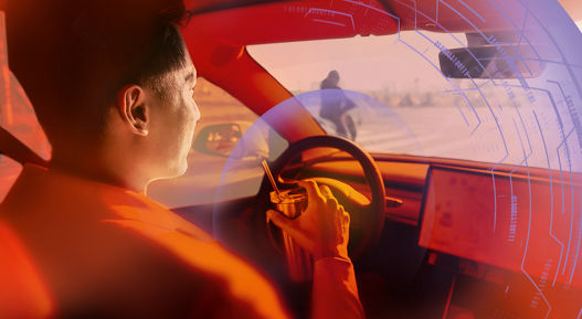 Driver inside a modern car holding the steering wheel, with an orange overlay and digital interface graphics representing autonomous driving and safety technology.