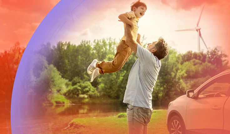 A person lifts a child joyfully in a scenic outdoor setting with lush greenery, a wind turbine in the background, and a car parked nearby, symbolizing family moments and sustainable living.