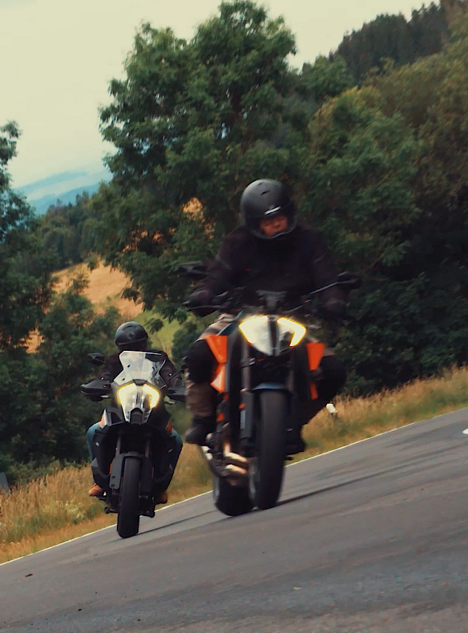 The photo shows two motorcyclists riding quickly one behind the other on a curve on a country road. Our Twin Motor Controller revolutionizes manual transmissions in motorcycles. 
