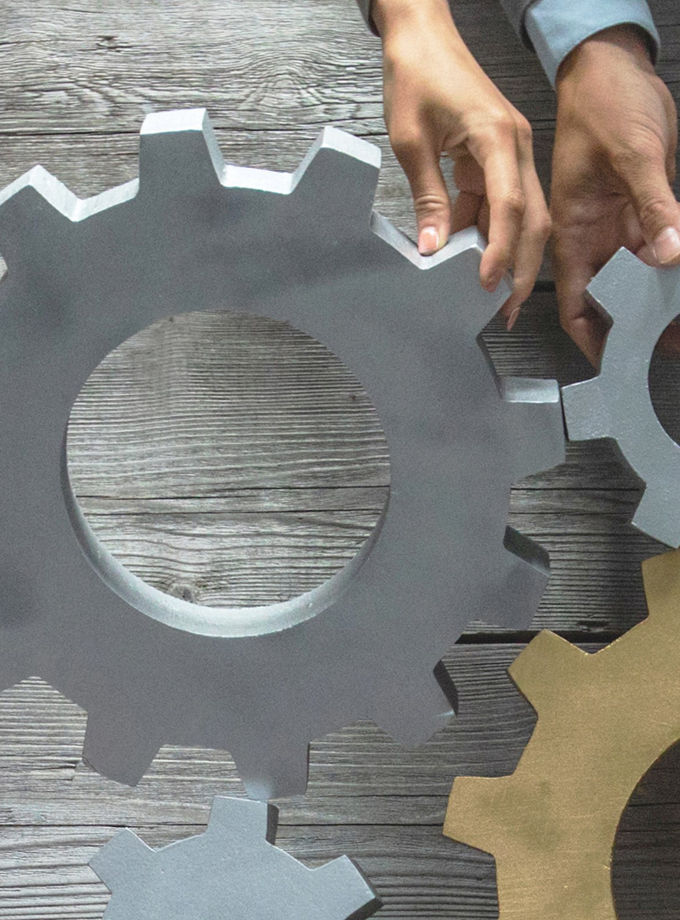 The image shows several hands holding gears together as a symbol of value-adding services.