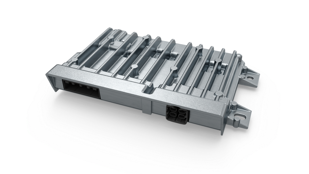 Close-up view of a vehicle control high-performance computer (HPC) unit with a robust metallic housing and integrated cooling fins. The design includes multiple mounting points and two connector ports on the front side for power and data interfaces. The structure emphasizes durability and heat dissipation for advanced automotive control systems.