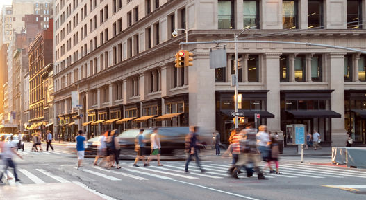 New York City street scene with crowds of people walking through the busy intersection of 23rd and 5th Avenue in Midtown Manhattan