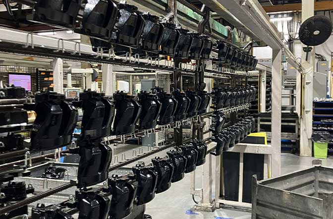The image shows a assembly line for zinc and zinc nickel coated automotive parts. AUMOVIO UK plating services - zinc and zinc nickel plating specialists.